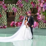 Newlyweds posing at floral backdrop, Legacy Venues outdoor wedding venue Los Angeles